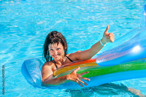 Woman swimming on inflatable beach mattress.
