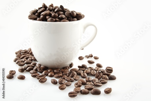 Coffee cup full of coffee beans on white