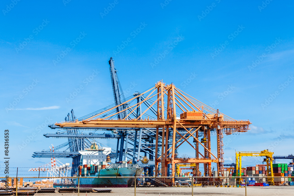 Cranes load containers on a large transport ship at trade port