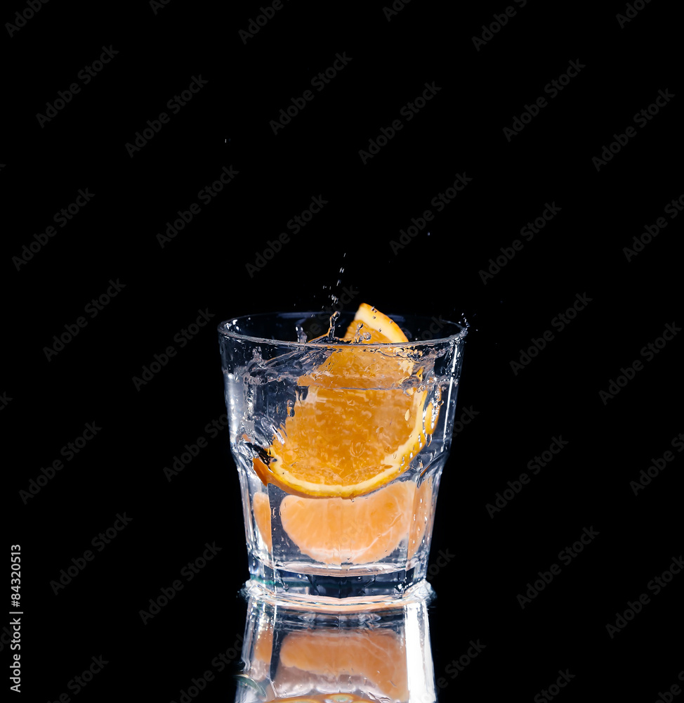 Slice of lemon splashing into a glass of water with a spray of water droplets Slice of lemon splashing into a glass of water with a spray of water droplets