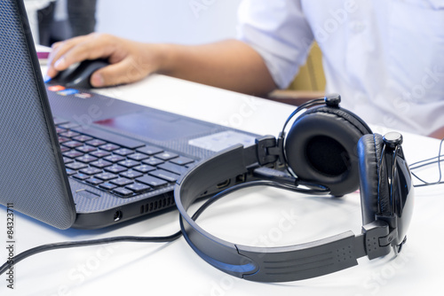 Man hand using keyboard and mouse to control laptop with headpho