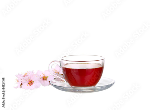 Cup of tea with a sprig of cherry blossoms isolated on white background.