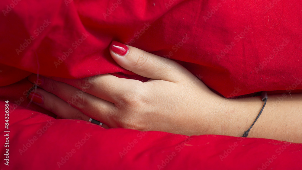 Woman hand under a red blanket Woman hand under a red blanket