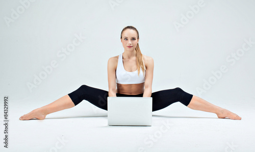 Girl makes yoga exercise online with laptop 