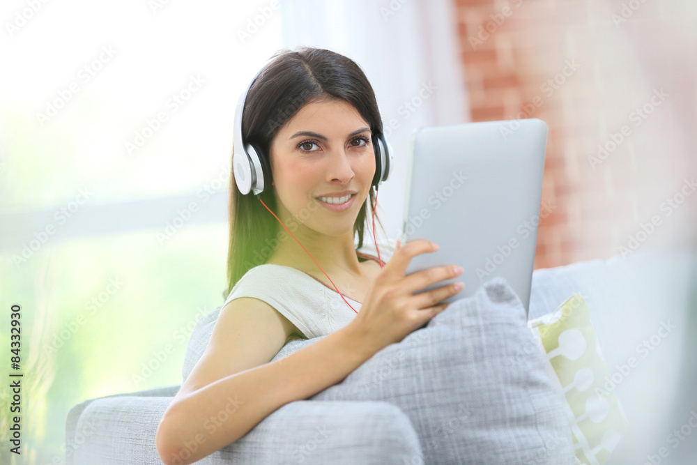 Young woman with tablet and headphones sitting in sofa Young woman with tablet and headphones sitting in sofa