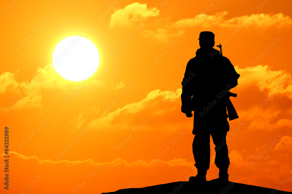 Silhouette shot of soldier holding gun with colorful sky and mountain 