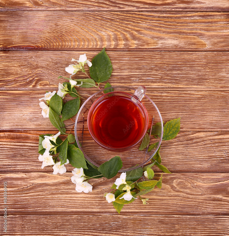 Fototapeta premium Herbal tea in a glass cup, fresh flowers on a background 