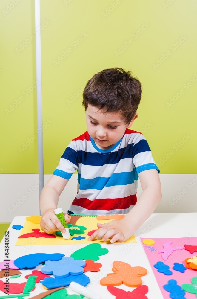 A preschool boy use glue for homework received from kindergarten A preschool boy use glue for homework received from kindergarten