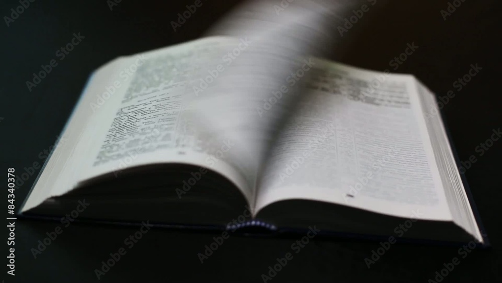 The Bible on a black background. Turning the pages of the Holy The Bible on a black background. Turning the pages of the Holy