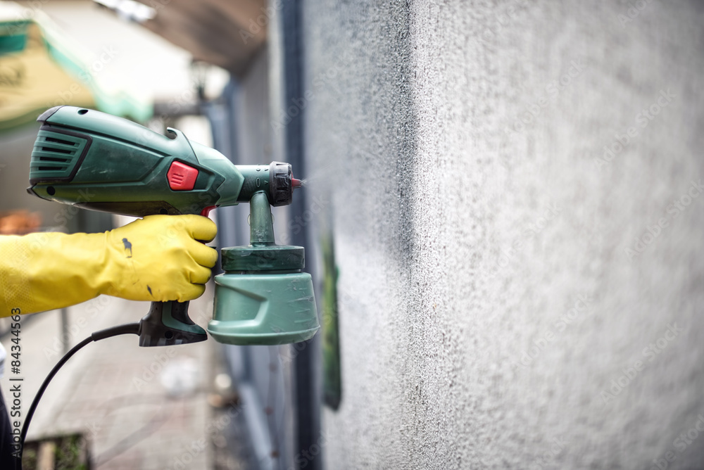Worker painting wall with paint using professional spray gun. Worker painting wall with paint using professional spray gun.
