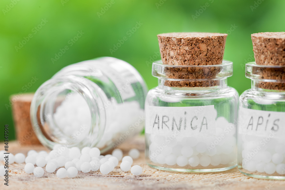 Three bottles of homeopathy globules on green background Three bottles of homeopathy globules on green background