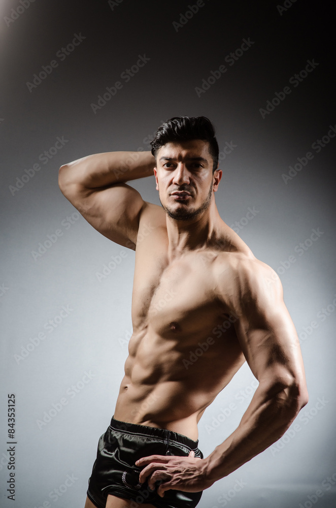 Muscular man posing in dark studio Muscular man posing in dark studio