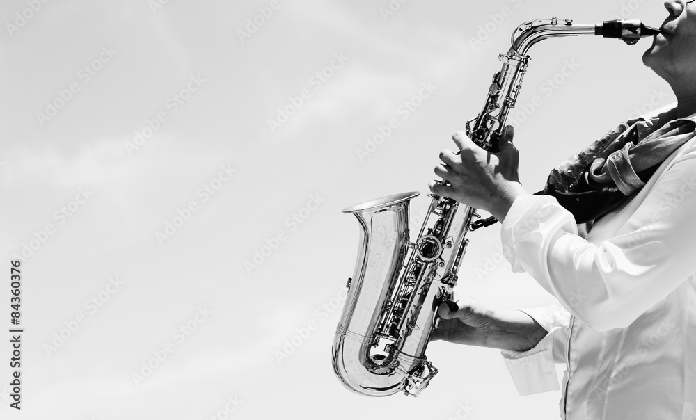 Obraz premium Saxophonist playing on saxophone on blue sky background