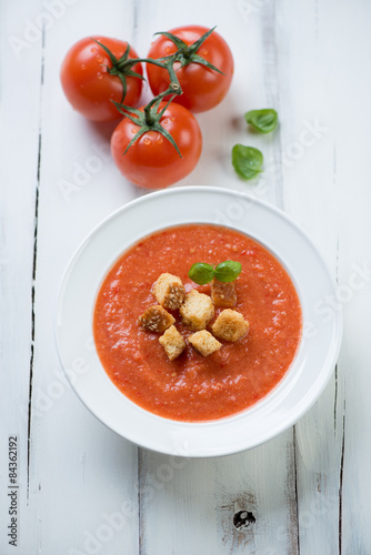Tomato soup gazpacho over white wooden background, above view