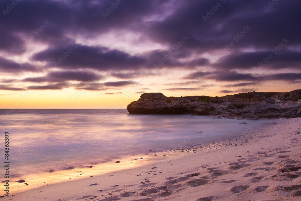 Obraz premium Early morning landscape of ocean over rocky shore and glowing su