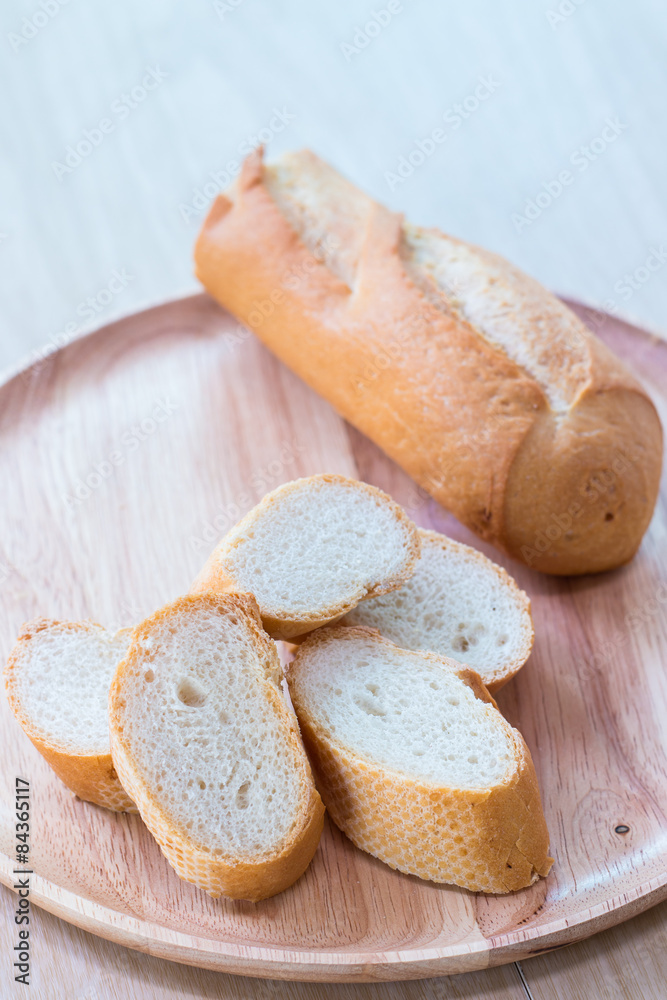 Sliced french bread baguette on wooden plate.Soft focus style