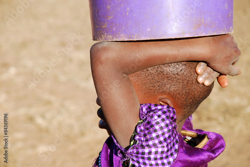 An African child with a bucket of water - Pomerini - Tanzania - photo