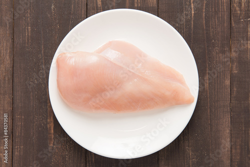 Raw chicken breast fillets on white dish.