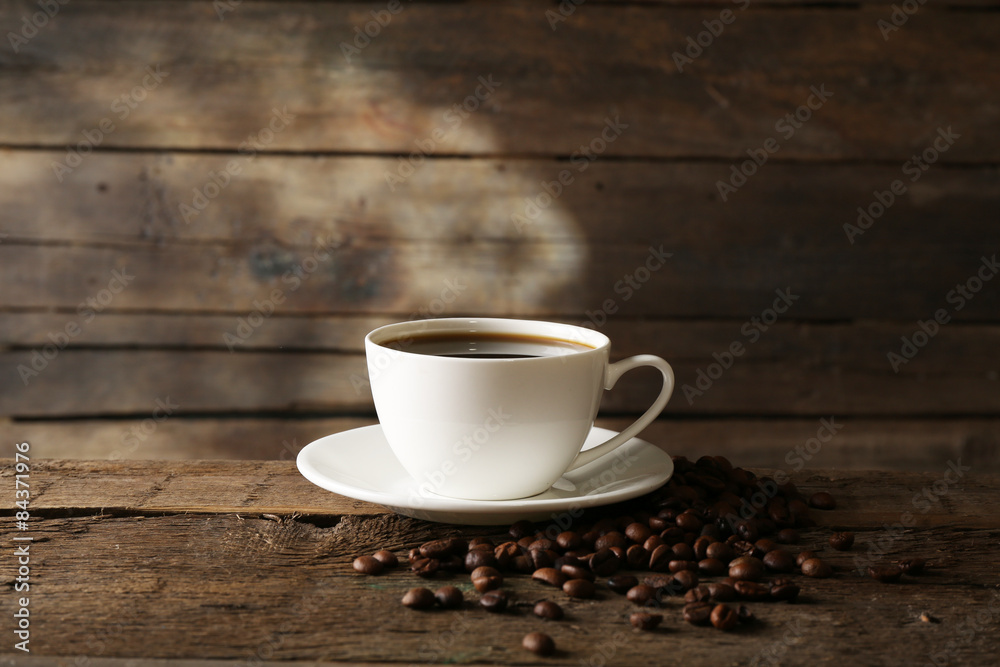 Cup of coffee with grains on wooden background