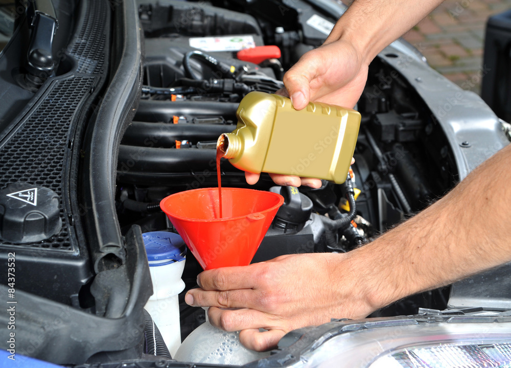 Pouring radiator leak repair liquid into a car cooling system