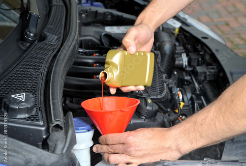 Fotografie Pouring radiator leak repair liquid into a car cooling system
