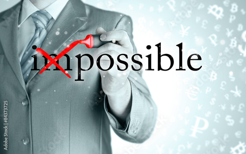 Businessman Hand turning the word Impossible into Possible with