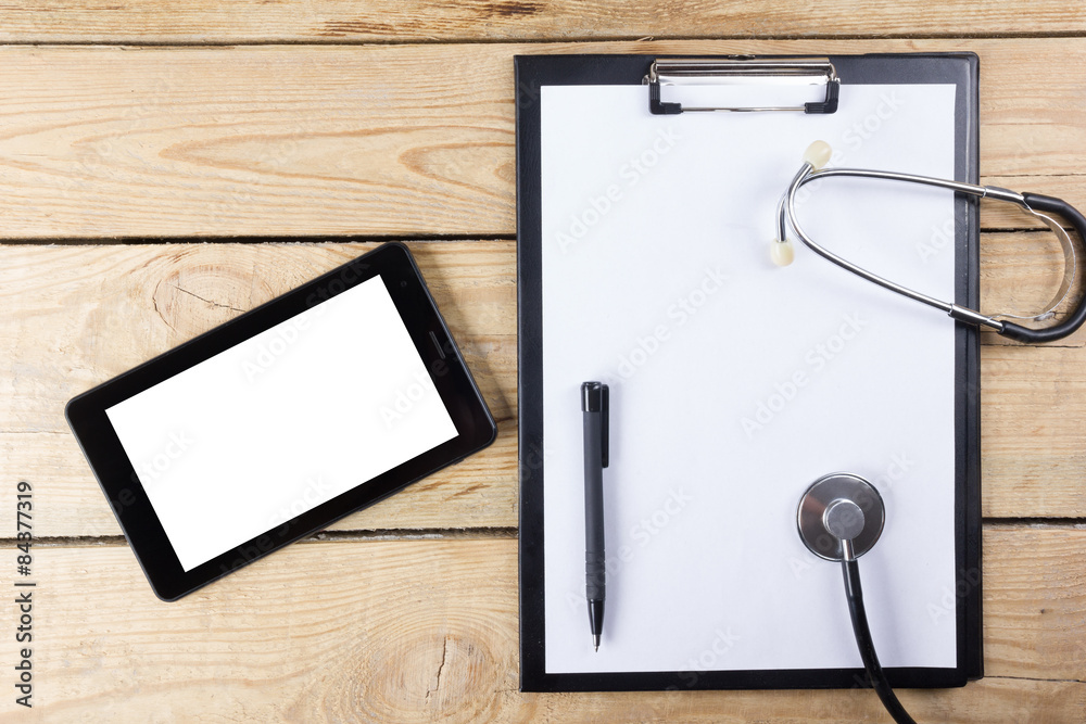 Workplace of a doctor. Tablet, stethoscope, black pen on wooden desk background. Top view Workplace of a doctor. Tablet, stethoscope, black pen on wooden desk background. Top view