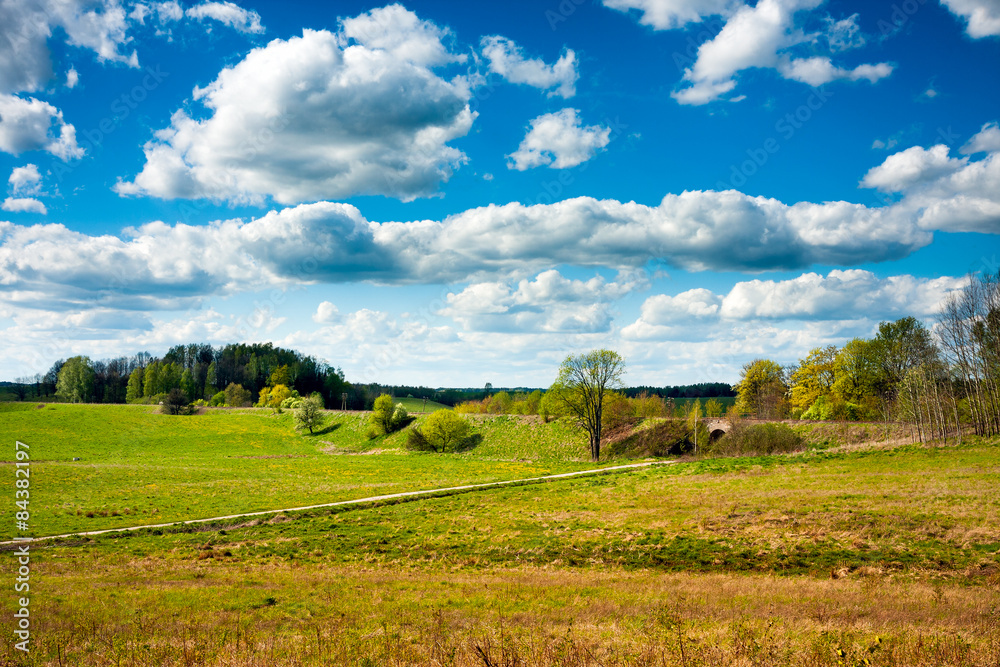 Countryside field and road, blue sky clouds