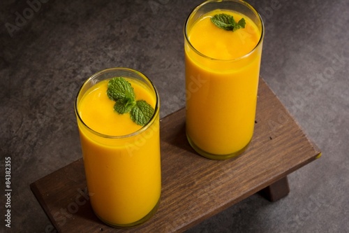 Mango Lassi with mint leaf on top on dark moody background photo