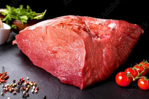 Carne fresca y cruda. Pieza entera de carne roja lista para cocinar a la parrilla o barbacoa. Fondo negro pizarra photo