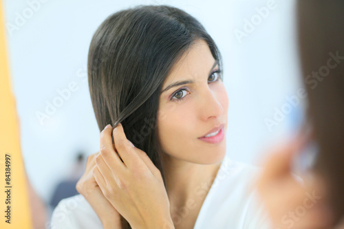 Portrait of beautiful young woman looking at her skin