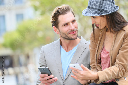 Trendy couple in town using smartphone