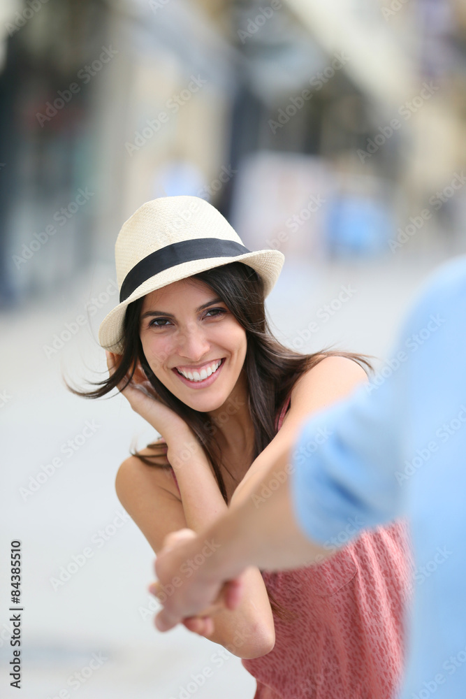 Cheerful brunette girl with hat holding boyfriend's hand Cheerful brunette girl with hat holding boyfriend's hand