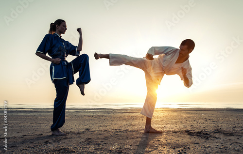 couple training in martial arts on the beach