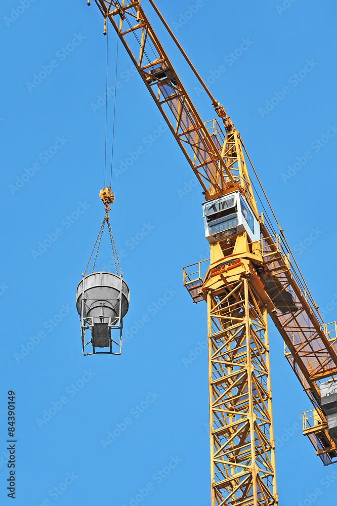 Crane lifting concrete mixer container against blue sky Crane lifting concrete mixer container against blue sky