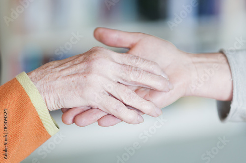 Frau haelt Hand von einer Seniorin