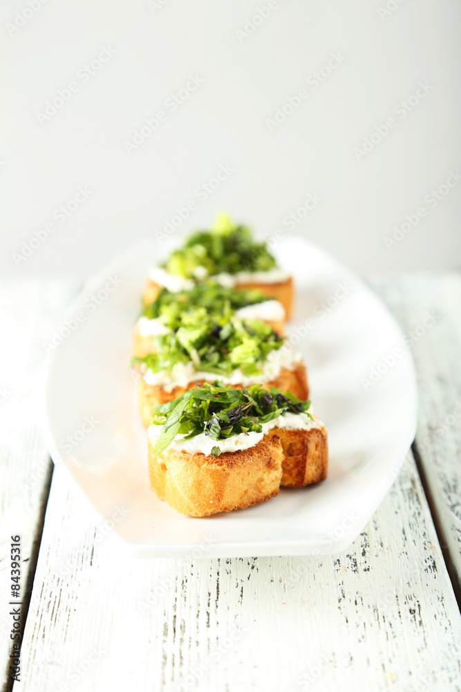 Tasty fresh bruschetta on plate on white wooden background