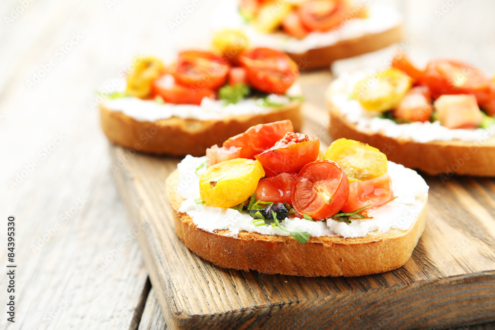 Tasty fresh bruschetta with tomatoes on cutting board on grey wo Tasty fresh bruschetta with tomatoes on cutting board on grey wo