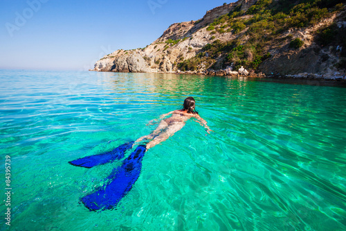 Woman swimming with flippers on the beach. Active holiday in sea
