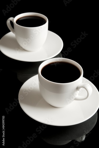 Cups of coffee with saucer isolated on black