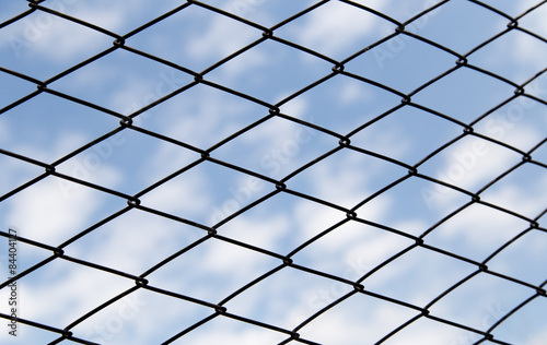 metal fence against the blue sky with clouds