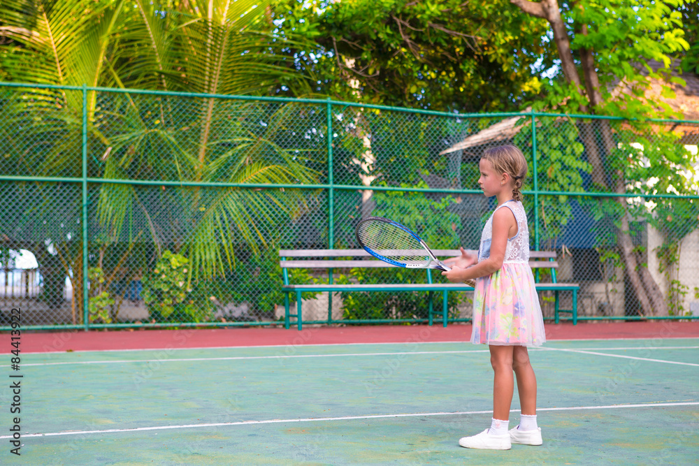 Little girl trying to play tennis on outdoor court
