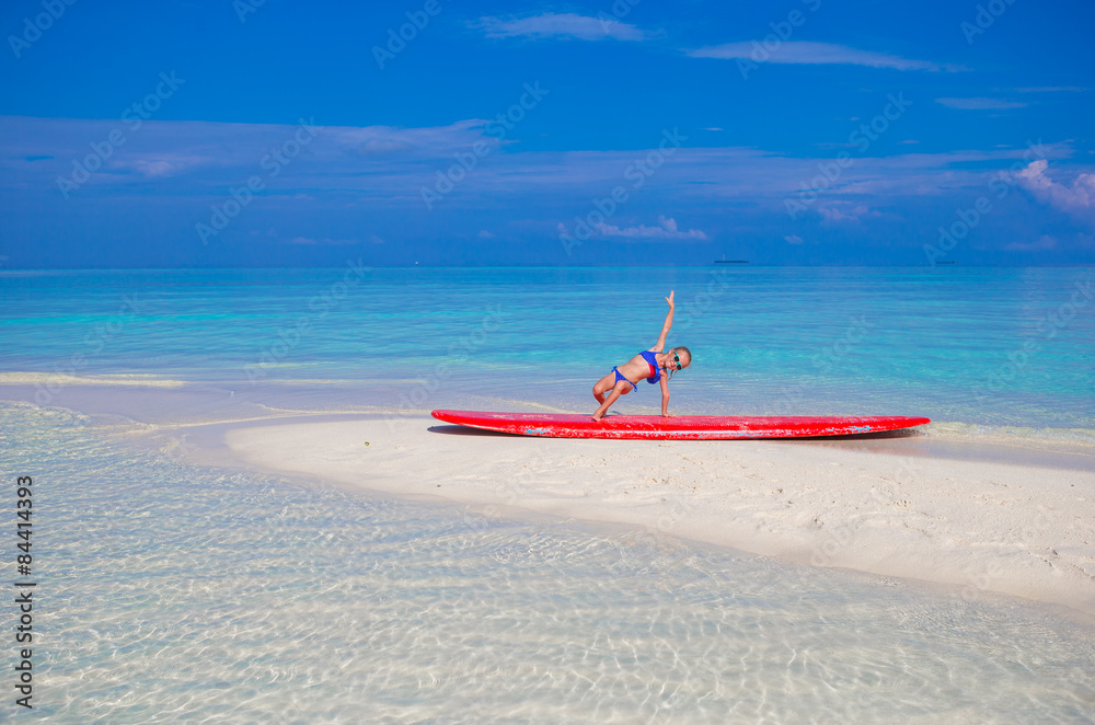 Little adorable girl on a surfboard in the turquoise sea Little adorable girl on a surfboard in the turquoise sea