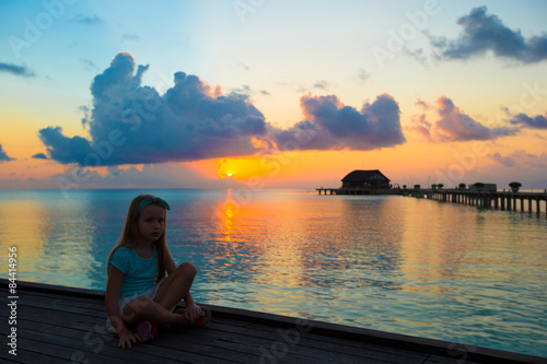 Silhouette of adorable little girl on wooden jetty at sunset © travnikovstudio