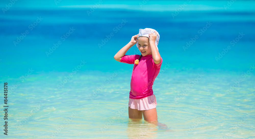 Adorable happy little girl have fun at shallow water on beach