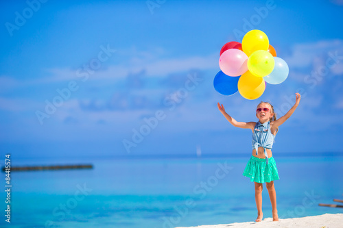Adorable little girl playing with balloons at the beach