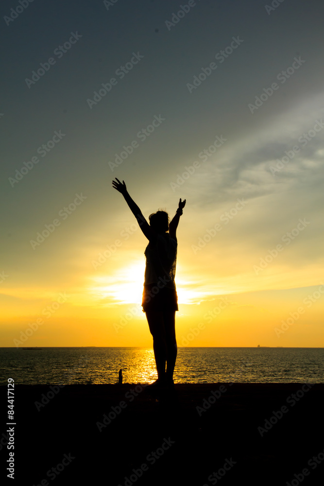 Silhouette of a woman against the sky at sunset