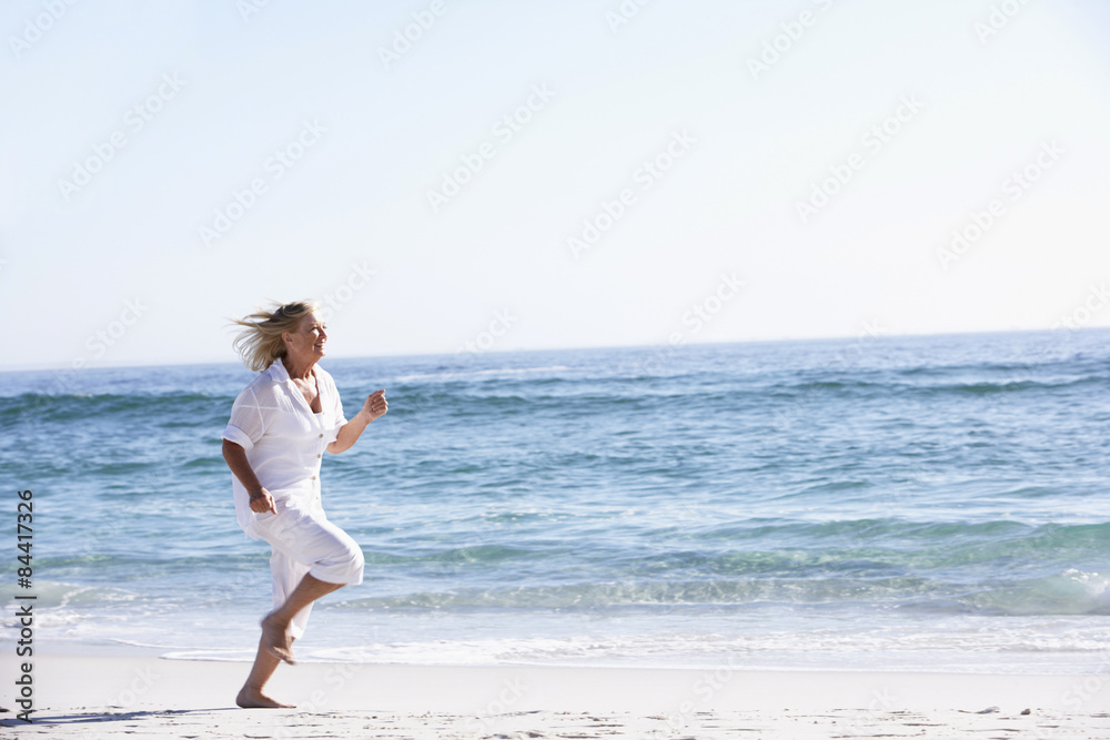Senior Woman Running along Sandy Beach Senior Woman Running along Sandy Beach