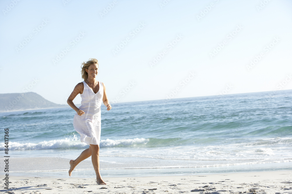 Casually Dressed  Young Woman Running Along Beach