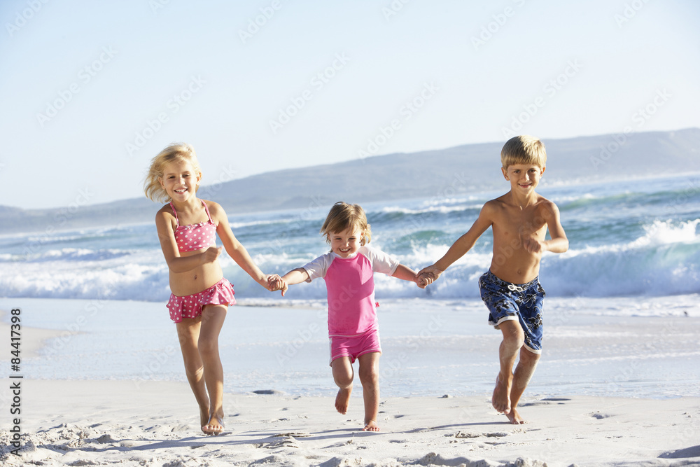 Group Of Children Running Along Beach In Swimwear